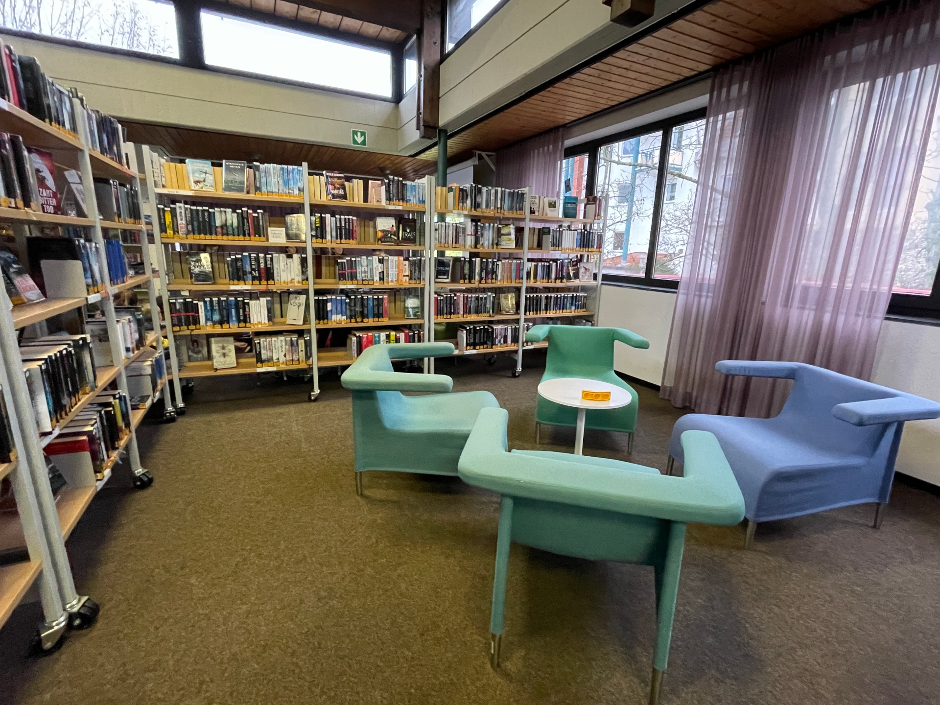 مكتبة نيدرودن العامة التصميم الداخلي للمكتبة العامة في نيدرودن مع أرفف كتب ومقاعد عصرية بألوان الباستيل بجوار نوافذ كبيرة