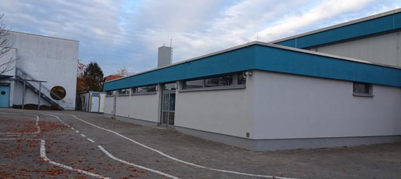 Гимназия Гимназията на Wilhelm-Busch-Schule, разпознаваема по синьо-белия си покрив и прилежащата детска площадка.