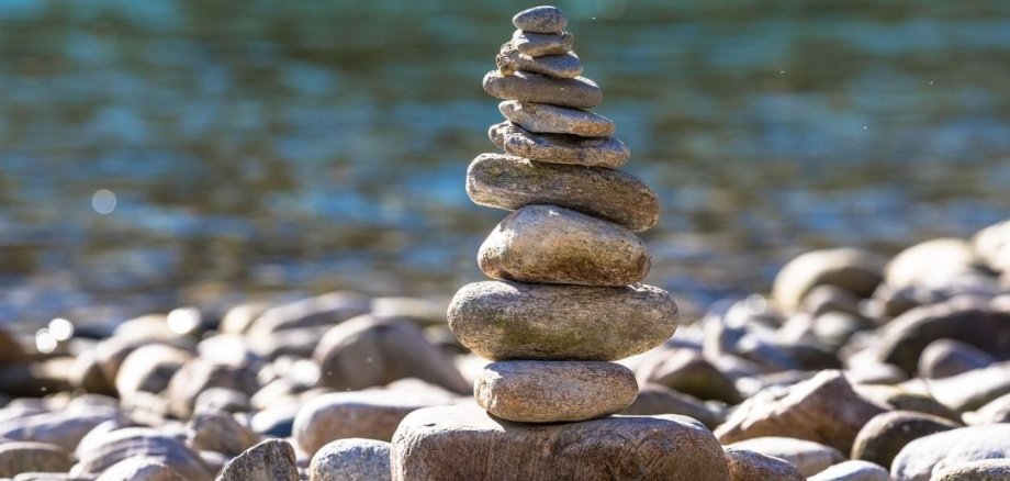 Tower of stacked stones on a gravel bed against a blurred water background