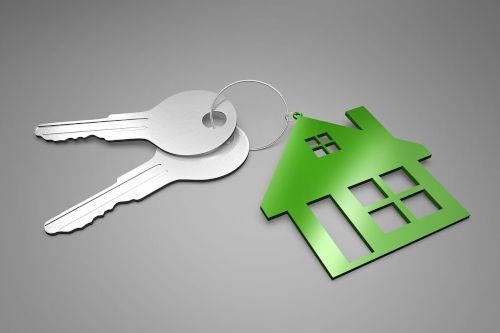 vhs Real Estate Two silver keys with a key ring on which hangs a green house symbol with windows.