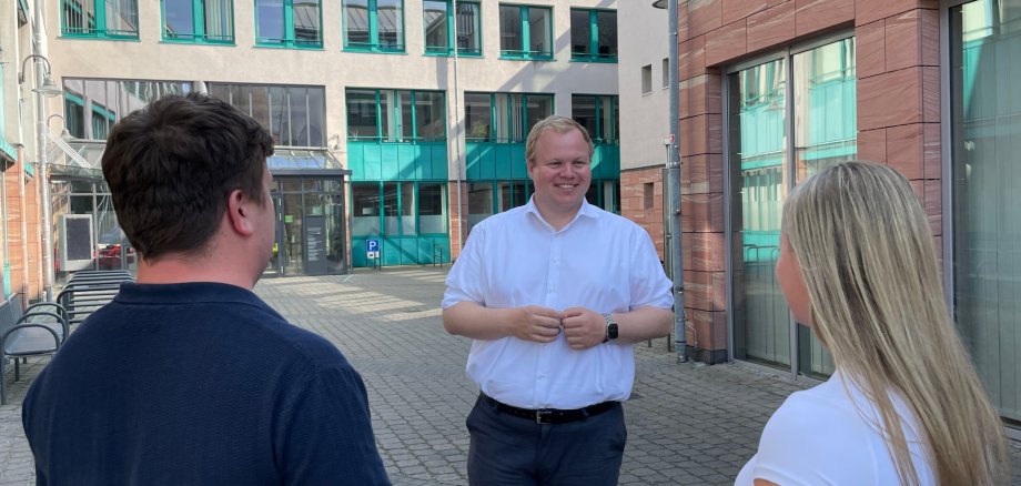 Mayor Max Breitenbach talks to two people in the inner courtyard of the town hall