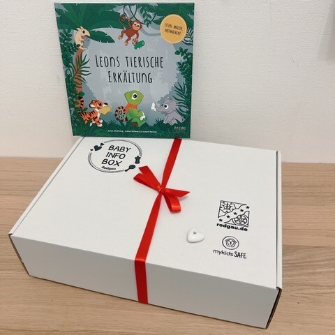 White baby info box with red ribbon and book White baby info box with red ribbon and book 'Leon's animal cold' with animal illustrations in the background