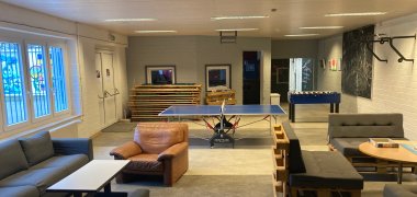 The picture shows the large room of the youth centre in the basement with table tennis table, foosball table and seating.