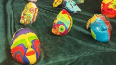 Youth Art Colourful, hand-painted masks with abstract patterns on green fabric, exhibited at Jugend Art