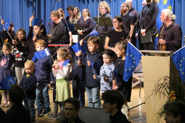 A group of children proudly hold European flags during the presentation of the flag of honour