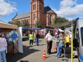 There are many stands with offers for senior citizens on the town hall forecourt. In the background, some visitors are sitting on beer benches.