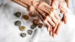 Two hands of an elderly person counting coins.