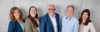 Five people stand in front of an exposed concrete wall on wooden planks - from left Laura Klein, Lena Fluks, Bardo Neuhäusel, Andreas Ernst, Jennifer Jäger