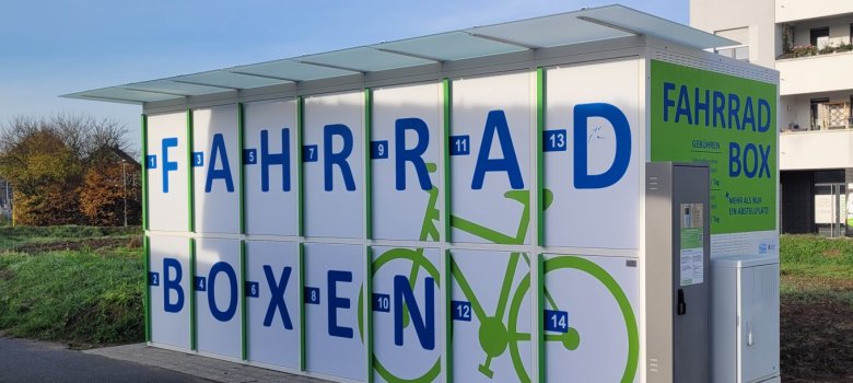 Bicycle boxes Nieder-Roden White bicycle box with blue lettering 'FAHRRAD BOXEN' and green bicycle pictogram at Nieder-Roden railway station.