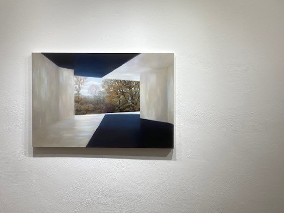 La pintura muestra un pasillo rectangular de color claro con sombras que da a un fondo boscoso con árboles desnudos.