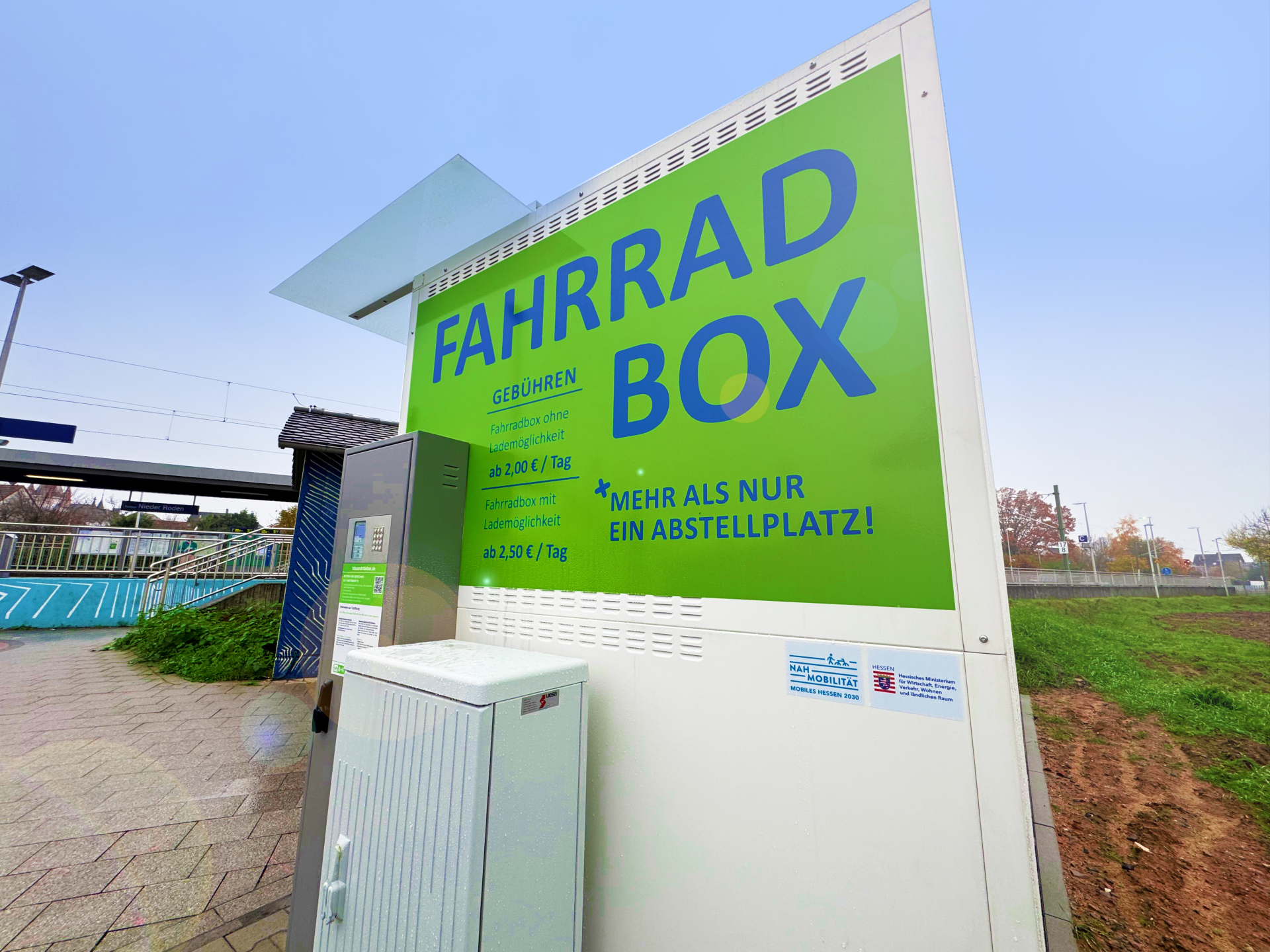 Caja para bicicletas Cartel verde con la inscripción "FAHRRAD BOX" e información sobre precios en los aparcabicicletas de la estación de ferrocarril de Nieder-Roden.