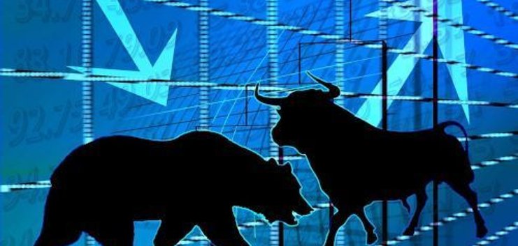 Siluetas negras de un oso y un toro sobre fondo azul con gráficos financieros y flechas apuntando hacia abajo.