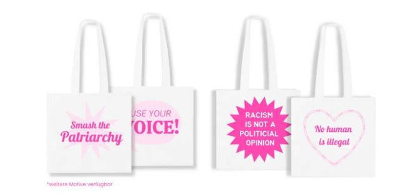 Cuatro bolsas de tela blanca con mensajes feministas y sociales: "Aplasta el patriarcado", "¡Usa tu voz!", "El racismo no es una opinión política", "Ningún ser humano es ilegal".