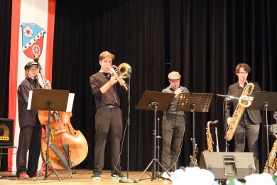 Cuatro músicos en el escenario del Kulturförderpreis, tocando el clarinete, el contrabajo, el trombón y el saxofón barítono