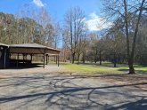 A la izquierda de la imagen está el edificio de madera cubierto del centro de ocio forestal, en el centro y a la derecha están la pradera y el bosque con vistas al Gänsbrüh en Dudenhofen.