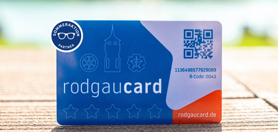 Promoción de verano de la rodgaucard Tarjetas Rodgaucards azules con texto en blanco, un código QR, símbolos y la inscripción «Promoción de verano para socios» sobre un fondo de madera