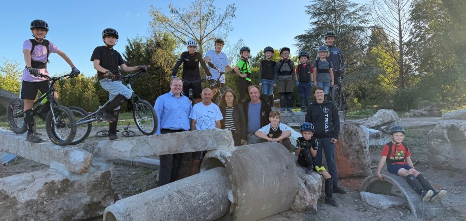 Un nouveau site pour la section trail du TSV Un groupe d'enfants et d'adultes, équipés de casques et de vélos, sur et autour de gros tuyaux en béton et de rochers, en plein air