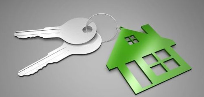 Deux clés en argent attachées à un porte-clés orné d'un pendentif vert en forme de maison