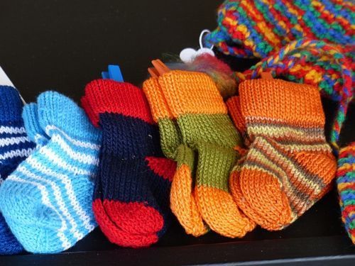 Plusieurs chaussettes tricotées à la main, de différentes couleurs et avec différents motifs, alignées les unes à côté des autres
