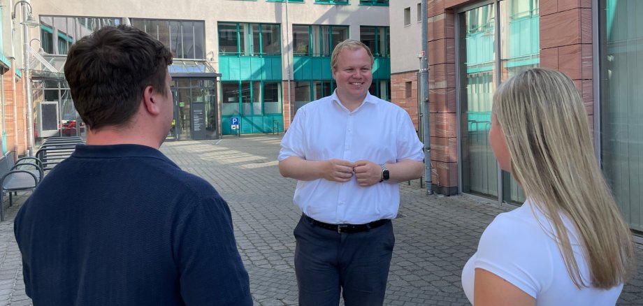 Le maire Max Breitenbach avec deux personnes dans la cour Le maire Max Breitenbach s'entretient avec deux personnes dans la cour de l'hôtel de ville
