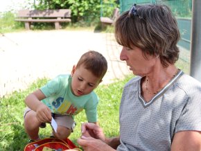Une participante au projet Grands-parents rêvés joue en plein air dans une prairie verte avec son "petit-fils rêvé".