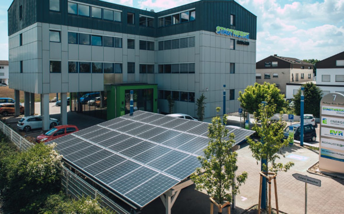 Services publics Bâtiment Un bâtiment blanc des services publics avec des panneaux solaires et des arbres au premier plan.