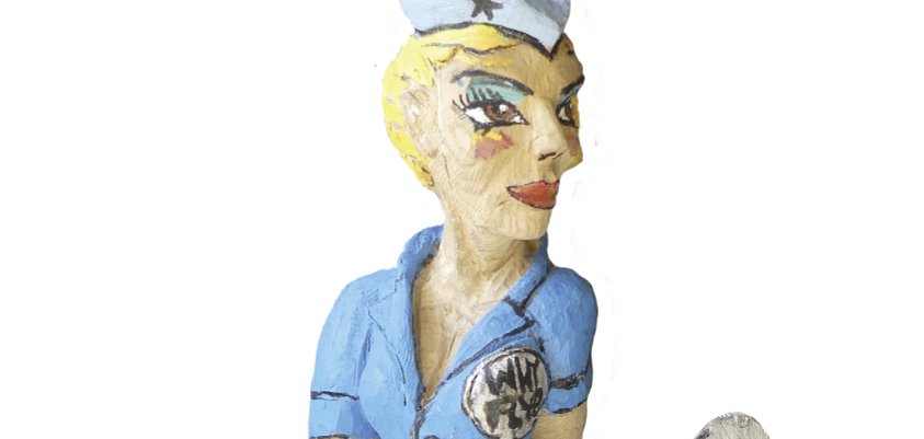 Scultura di un pilota seduto in uniforme blu, su un aereo. Materiale: quercia rossa, altezza circa 60 cm, anno: 2019, iscrizione: "Pop-A-Roc".