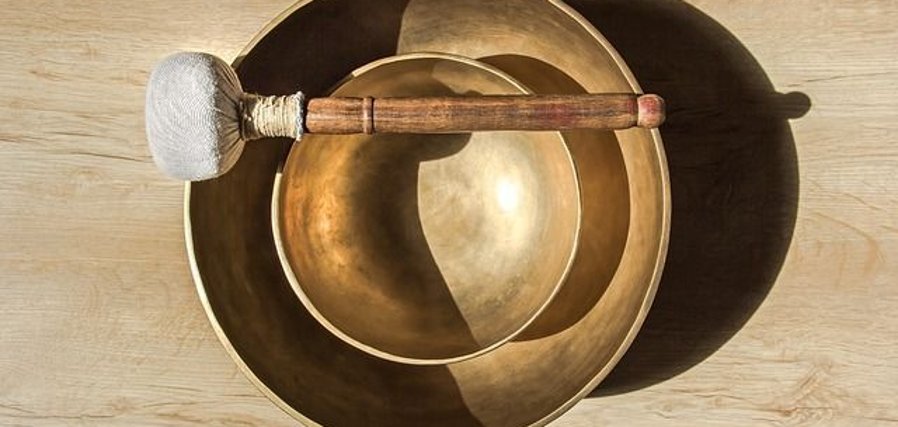 Cerimonia delle campane tibetane Due campane tibetane incastrate l'una nell'altra, con un martelletto appoggiato sulla campana superiore, su un tavolo di legno chiaro