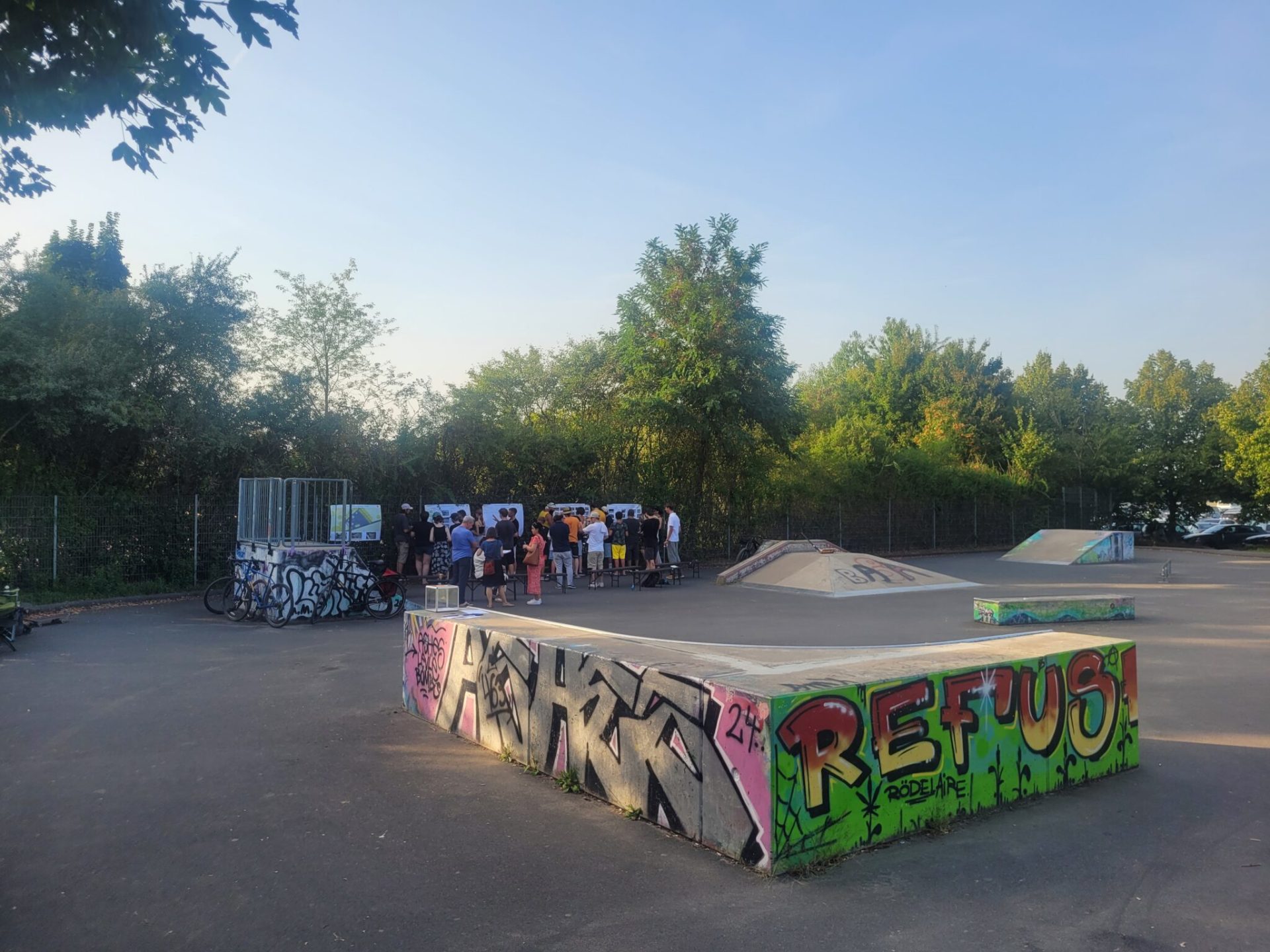 Pista da skate presso lo stabilimento balneare con diverse rampe e un gruppo di persone sullo sfondo; una rampa è ricoperta di graffiti colorati