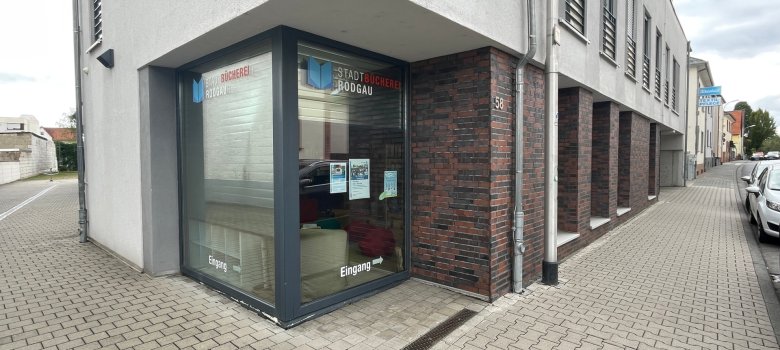 Biblioteca pubblica di Jügesheim Ingresso della biblioteca pubblica di Jügesheim in un edificio moderno con facciata in vetro e segnaletica