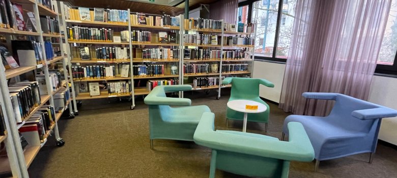 Biblioteca pubblica di Niederroden Interno della biblioteca pubblica di Niederroden con scaffali e sedute moderne in colori pastello accanto a grandi finestre