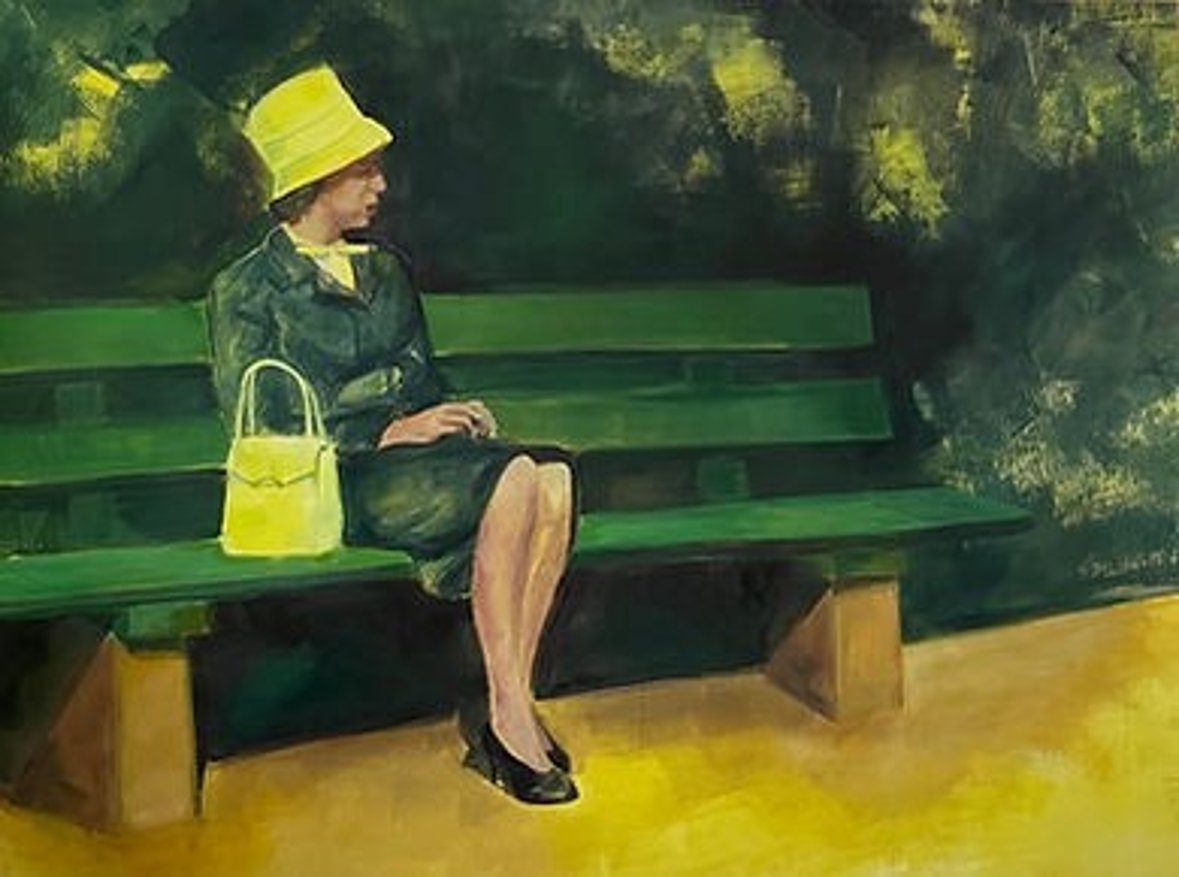 Immagini di Beate Perschbacher Donna in abito scuro e berretto giallo siede su una panchina verde del parco accanto a una borsetta gialla all'ombra degli alberi