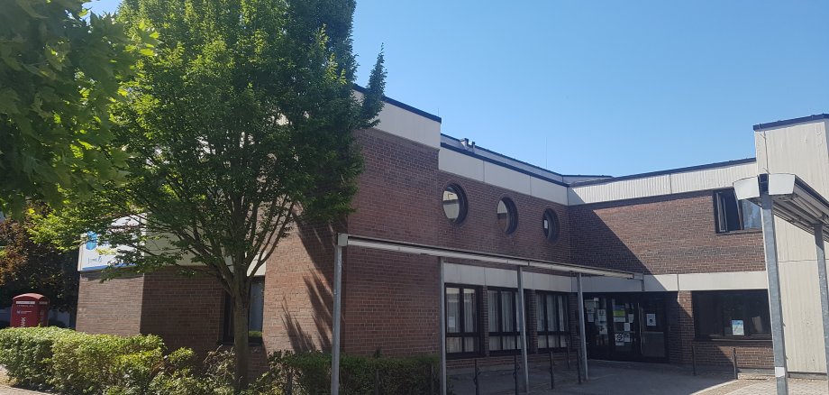 Ingresso del centro sociale di Niederroden con facciata in mattoni, diverse finestre rotonde e alberi in primo piano
