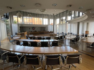 Sala riunioni rotonda con sedie in legno e metallo e grandi finestre nella sala consiliare del municipio di Jügesheim