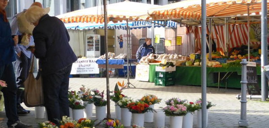 Mercato settimanale a Jügesheim con bancarelle di fiori, verdure e prodotti da forno sotto tende a righe
