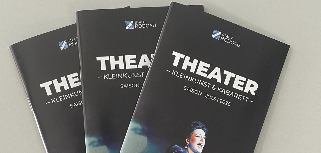 Trzy czarne broszury teatralne z tytułem "THEATER - KLEINKUNST & KABARET" na sezon 2025/2026, przedstawiające osobę w białym kostiumie.