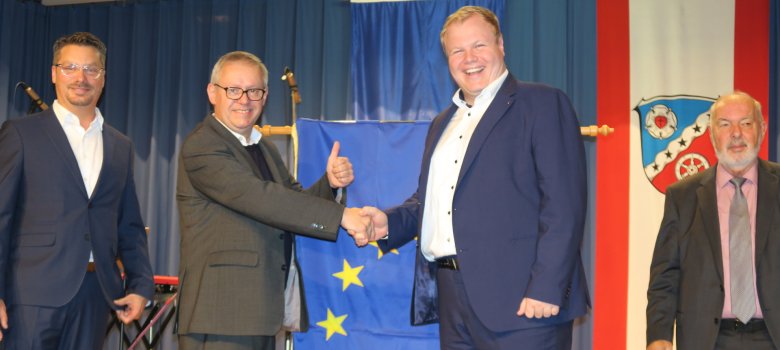 Przyznanie flagi honorowej Rady Europy Na scenie, od lewej do prawej, stoją były pierwszy radny Schüssler, Pierre-Alain Fridez, członek Zgromadzenia Parlamentarnego Rady Europy, burmistrz Breitenbach i przewodniczący Rady Miasta Kaiser, a w tle flaga honorowa i flaga z herbem Rodgau.