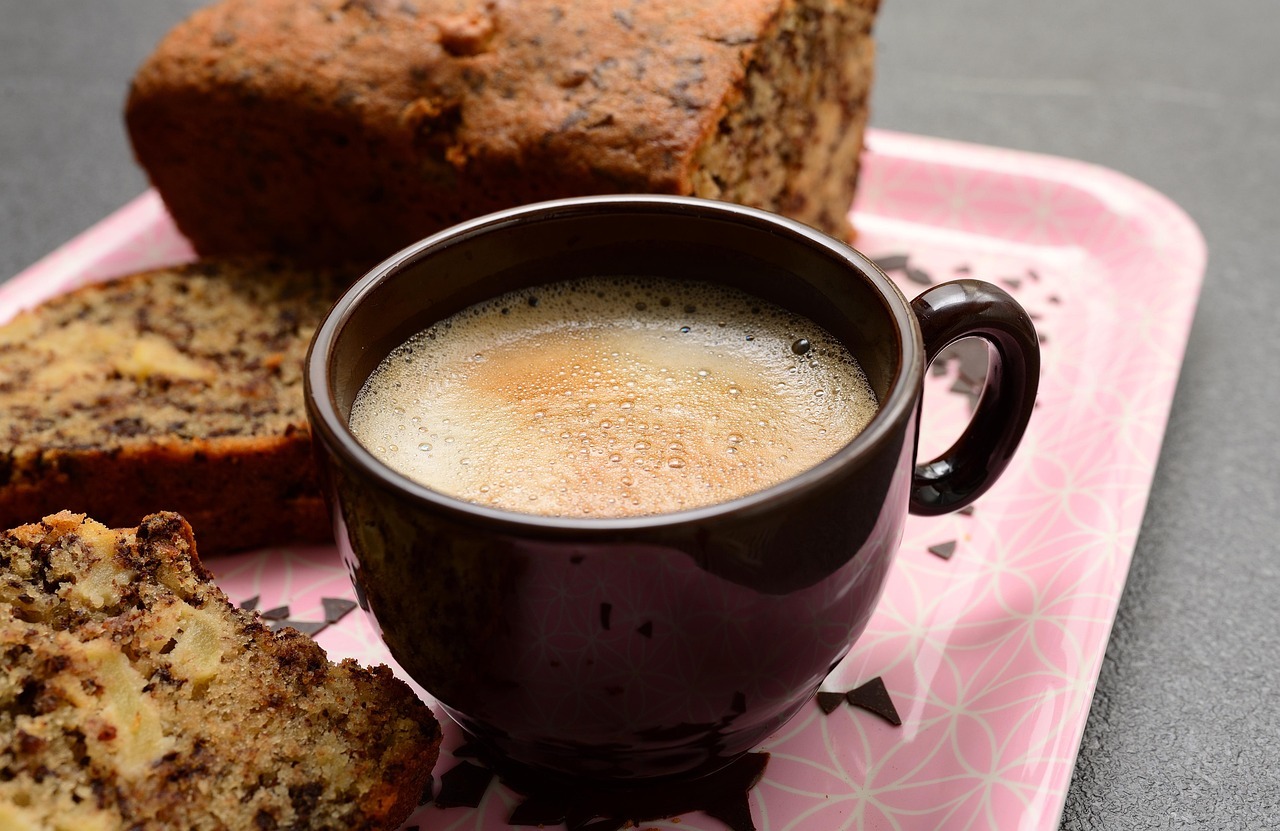 Serviços públicos café do cemitério Chávena de café preto numa bandeja cor-de-rosa, rodeada por duas fatias de bolo e um pão de forma inteiro.