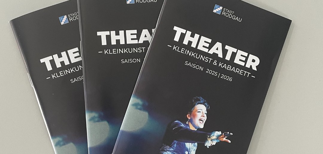 Três brochuras de teatro a preto com o título "THEATER - KLEINKUNST & KABARET" para a época de 2025/2026, com uma pessoa vestida de branco.