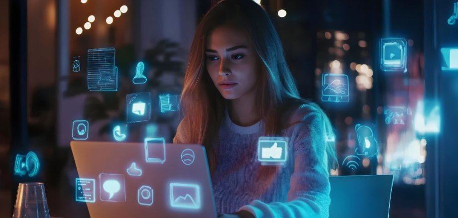 Pessoa sentada em frente a um computador portátil com ícones flutuantes e brilhantes de aplicações digitais num ambiente escuro