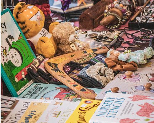 Mesa com livros infantis, peluches, brinquedos de madeira e bijutaria numa feira da ladra Mesa com livros infantis, peluches, brinquedos de madeira e bijutaria numa feira da ladra