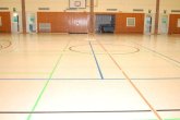 Vista interior do pavilhão desportivo de Jügesheim, equipado com um campo de basquetebol e marcações no chão.