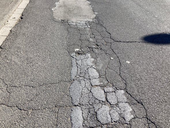 Reamenajarea străzii Wilhelm-Leuschner-Straße Prim plan al unei porțiuni de drum grav deteriorate și crăpate, cu marcaje rutiere decolorate, pe Wilhelm-Leuschner-Straße
