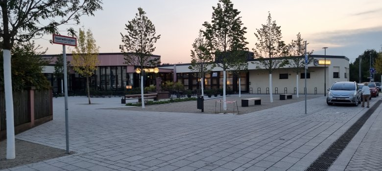 Curtea din fața centrului comunitar Dudenhofen Curtea din fața centrului comunitar din Dudenhofen cu copaci și mașini