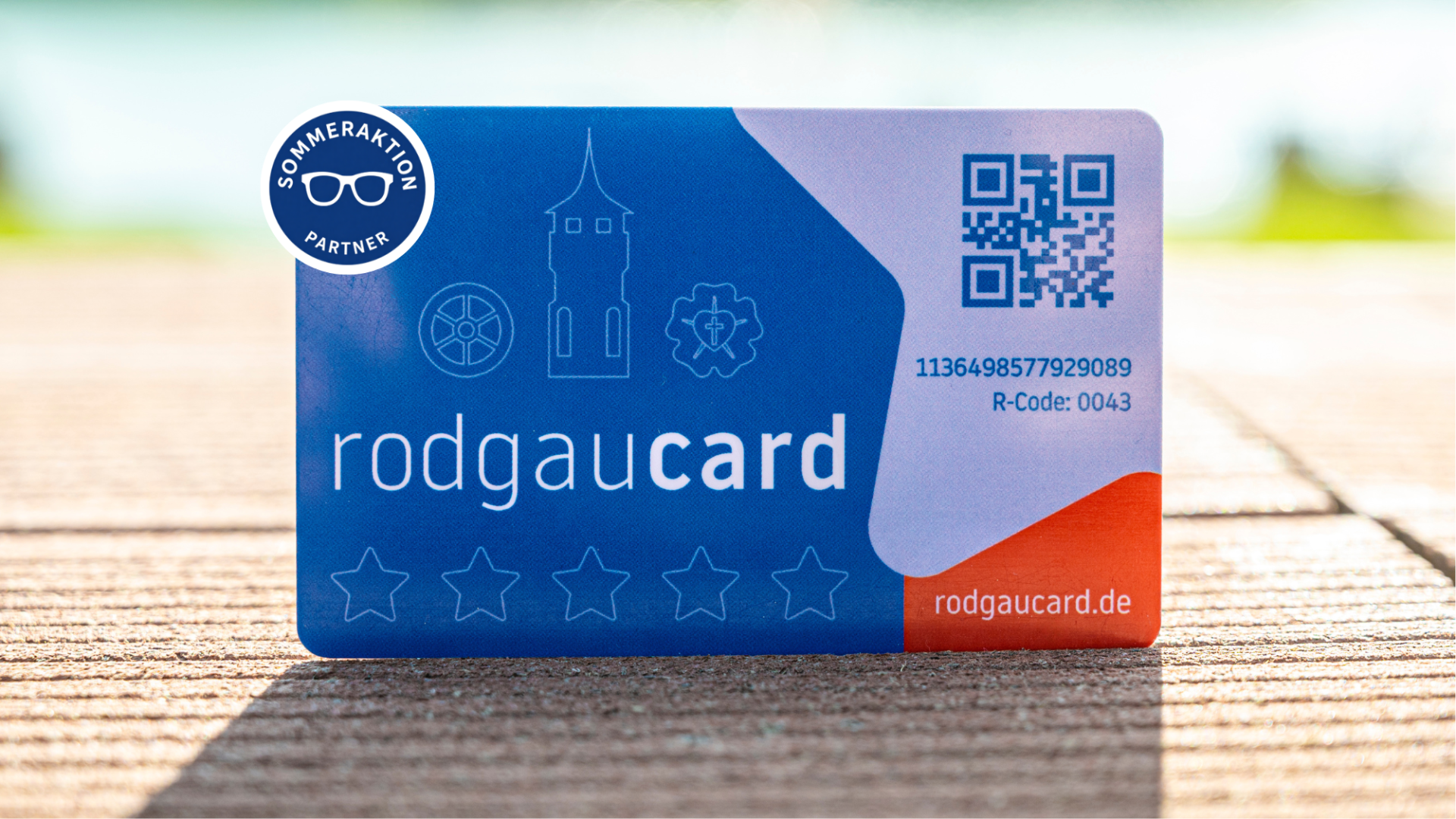 Синие карточки Rodgaucards с белым текстом, QR-кодом, символами и надписью «Партнер летней акции» на деревянном фоне