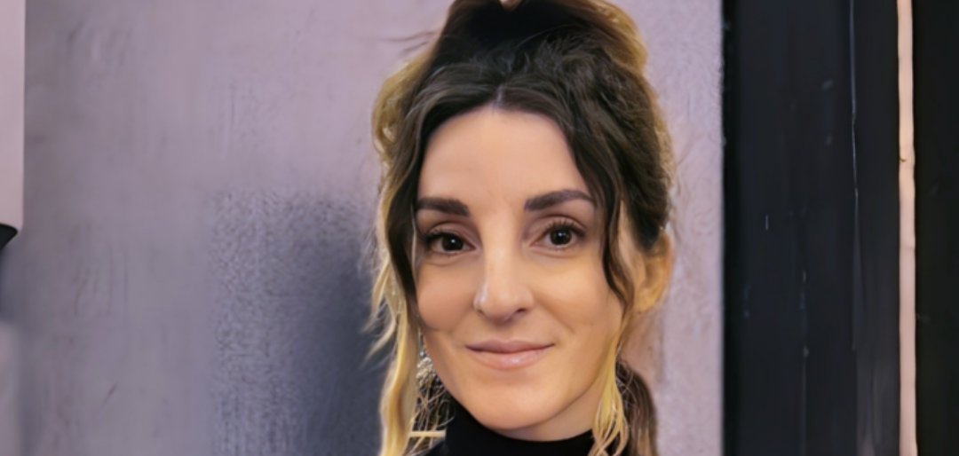 "Gündönümü Cinayeti" okunuyor "Sonnwendmord" (Gündönümü Cinayeti) kitabının yazarı Andrea Walter'ı görüyorsunuz. Saçını topuz yapmış ve iki tutamını öne doğru uzatmış. Üstü siyah ve yakalı.