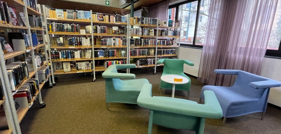 Інтер'єр публічної бібліотеки Нідерродену з книжковими полицями та сучасними сидіннями в пастельних тонах біля великих вікон