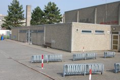 Зовнішній вигляд спортивного залу Nieder-Roden, оточеного парканом і обладнаного стійками для велосипедів.