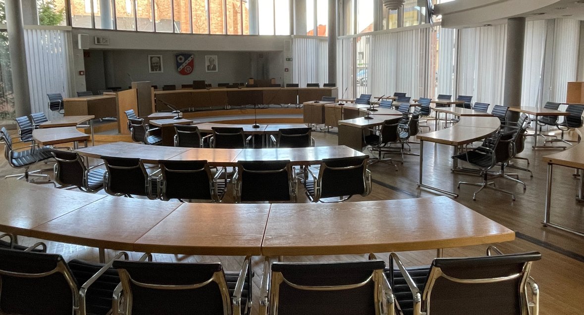 Кругла зала засідань з дерев'яними та металевими стільцями і великими вікнами в залі засідань ратуші в Юґесгаймі